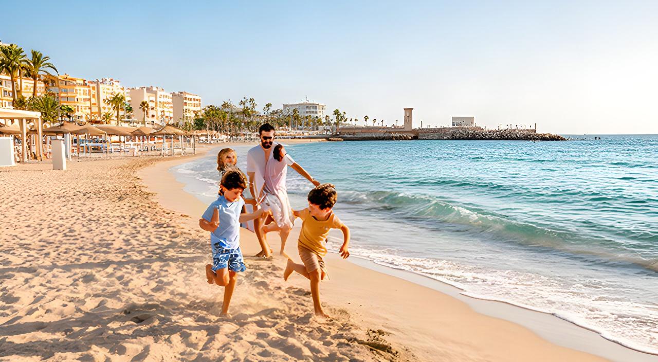 Familia con niños jugando en una playa de arena fina de Vinaròs junto al paseo marítimo